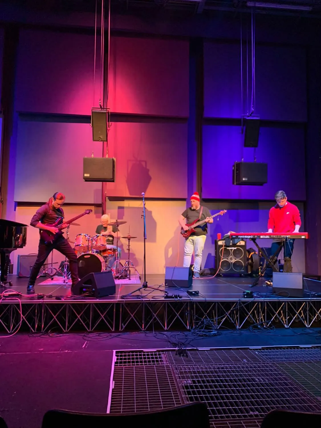 Jamie performing electric guitar on stage with a full band